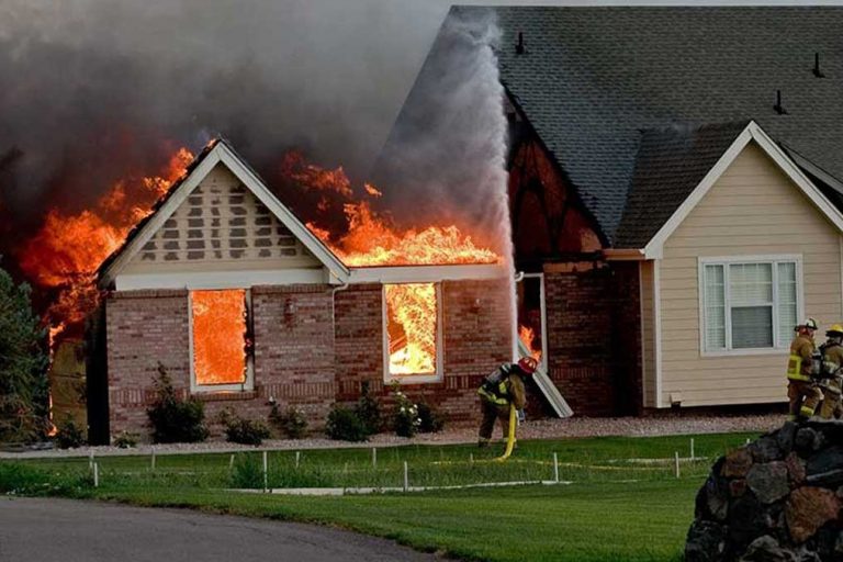 Fire fighters hosing down a house that's on fire
